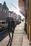 Finland, Helsinki, Businessman walking along city sidewalk