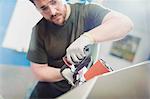 Worker using sander in steel factory