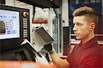 Worker with part at control panel in steel factory