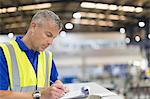 Supervisor writing on clipboard in steel factory