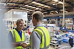 Smiling supervisor and worker handshaking in steel factory