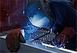 Welder using welding torch in steel factory