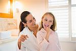 Mother and daughter brushing teeth in bathroom