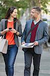 Business couple walking and talking on sidewalk