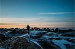 Man walking on icy mounds in remote landscape, Hofn, Iceland
