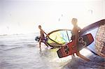 Couple walking into surf with kiteboard equipment