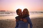 Portrait smiling couple hugging on sunset beach