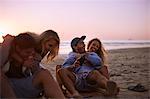 Playful couples hanging out on sunset beach