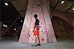 Japanese climbing athlete getting ready to climb gym wall