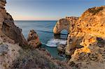 Sunrise on the cliffs and turquoise water of the ocean, Praia da Marinha, Caramujeira, Lagoa Municipality, Algarve, Portugal, Europe