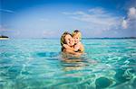 Enthusiastic mother hugging son in tropical ocean