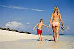 Mother and son walking on sunny tropical beach