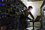 Server room technician working at laptop