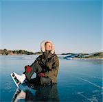 Sweden, Uppland, Varmdo, Bjorno, Mid adult woman sitting on frozen lake