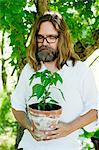 Sweden, Sodermanland, Man standing with eyes closed holding potted plant