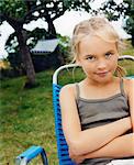 Sweden, Blonde girl (10-11) sitting in folding chair in garden