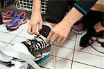 Sweden, Young woman tying shoelaces in locker room