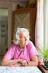 Sweden, Ostergotland, Finspang, Senior woman looking through window