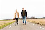 Sweden, Ostergotland, Mjolby, Teenage girl (14-15) and young man walking along country road