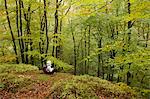 Sweden, Skane, Soderasens National Park, Klova Hallar, Mid adult woman sitting in forest