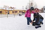 Sweden, Vasterbotten, Umea, Mother helping daughter (6-7) with ice skates