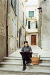 France, Languedoc-Roussillon, Sauve, Young tourist sitting on steps and looking at map