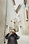 France, Languedoc-Roussillon, Sauve, Young tourist with camera in narrow street