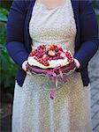 Sweden, Woman carrying cake topped with fresh berries