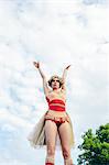 Sweden, Uppland, Hagaparken, Young woman acrobat with arms outstretched against sky