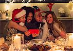 Playful young women with dog taking selfie at Christmas dinner