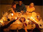 Overhead view friends toasting champagne glasses at candlelight Christmas dessert