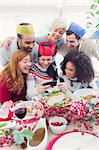 Friends in paper crowns taking selfie at Christmas dinner