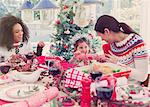 Mother and daughter pulling Christmas cracker at dinner