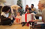 Friends and family opening Christmas gifts in living room