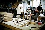 A man working in a furniture maker's workshop assembling a chair.