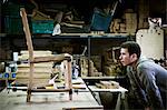 A man working in a furniture maker's workshop assembling a chair.