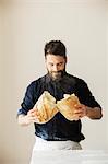 Baker holding two freshly baked loaves of bread.