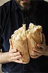 Close up of a baker holding two freshly baked loaves of bread.