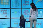 Mother and daughter standing in front of graphical screens showing educational images