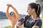 Young woman adjusting smartphone, attached to arm, for exercising