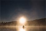 Senior couple canoeing on lake at sunset