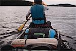 Mid adult woman canoeing on lake, rear view