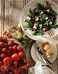 Mediterranean salad, feta cheese, black olives, sun dried tomatoes, salad leaves with fresh tomatoes in basket, overhead view