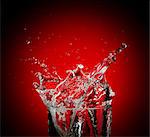 Water and droplets splashing against red background