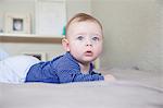 Portrait of blue eyed baby boy lying on bed