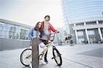 Girl and man with BMX and skateboard in urban area