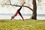 Side view of woman bending forward, leg raised in yoga position