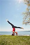 Side view of woman doing headstand, legs apart