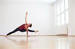 Woman in exercise studio arm and leg raised in yoga position