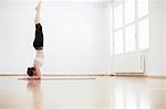 Side view of woman in exercise studio doing handstand